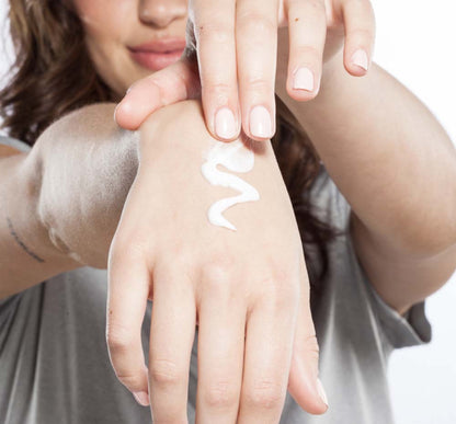 A woman is applying on her hand moisturizing Sugar Moon Dip Back To Youth Ageless Mousse by FarmHouse Fresh to calm her dry skin.