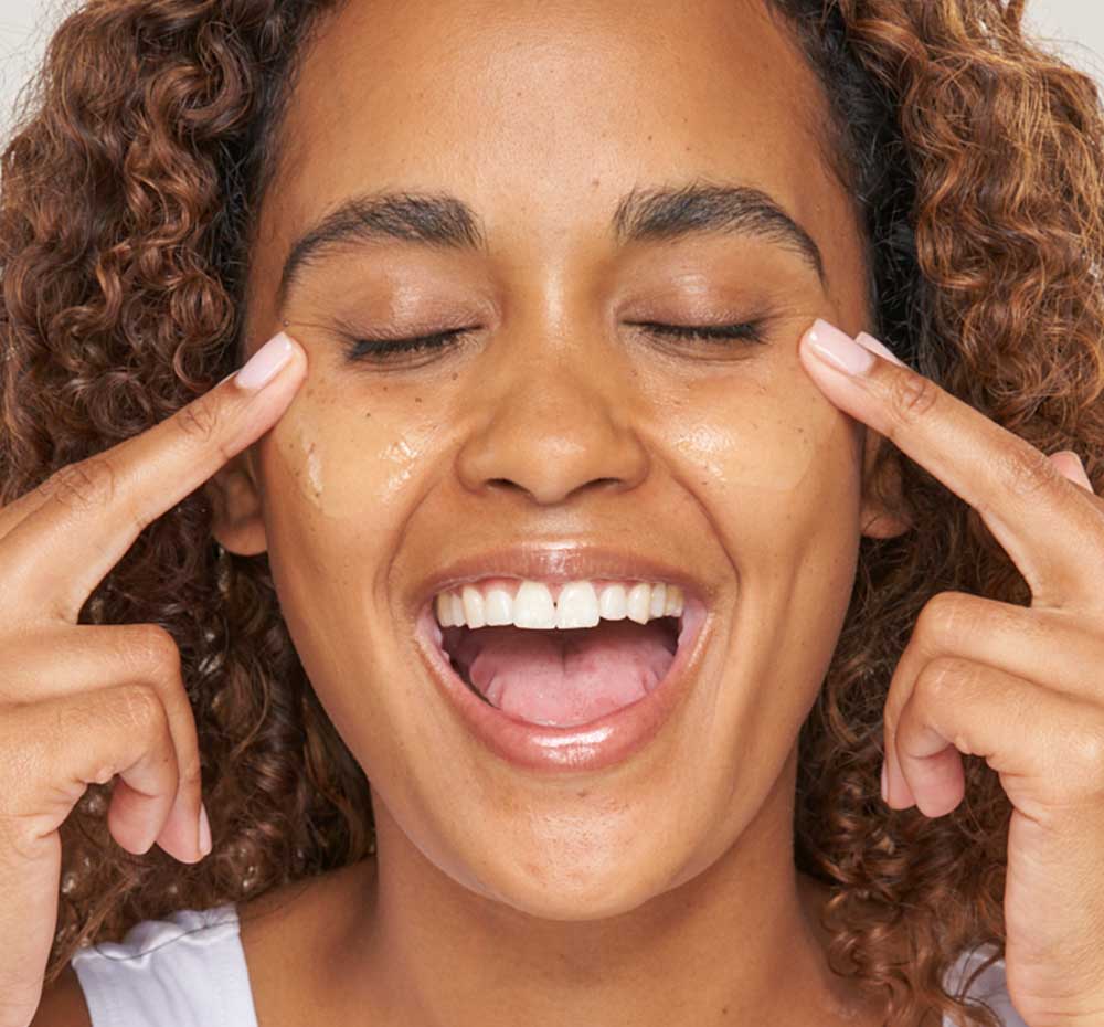 A woman is applying FarmHouse Fresh Green Fixer Calming Elixir Organic Matcha Face Serum on her face to replenishes moisture and soothe her complexion.