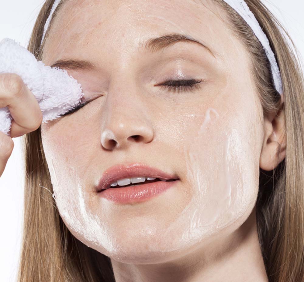 A woman removing her makeup with Farmhouse Fresh Green Tea Milk Wash that nourishes skin.