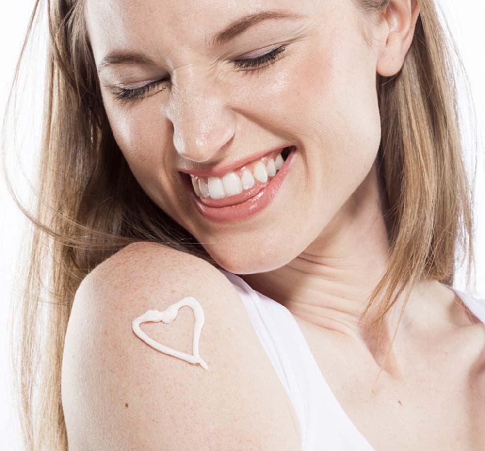 A woman with Farmhouse Fresh Honey-Chai Steeped Milk Lotion on her shoulder in a shape of a heart, enjoying the warm fall scent notes of the product.