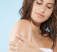 A woman exfoliating her arm with Farmhouse Fresh Honey Lavender sea salt body scrub.