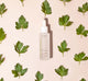 A bottle of FarmHouse Fresh Hyaluronic Booster next to parsley leaves that represent the locally-grown ingredients.