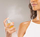 A woman is misting her face with alcohol-free Illumination Juice Facial Toner by FarmHouse Fresh to visibly brighten and even the look of skin.