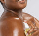 A woman is applying Juniper Ale body oil by FarmHouse Fresh to deeply moisturize her skin.