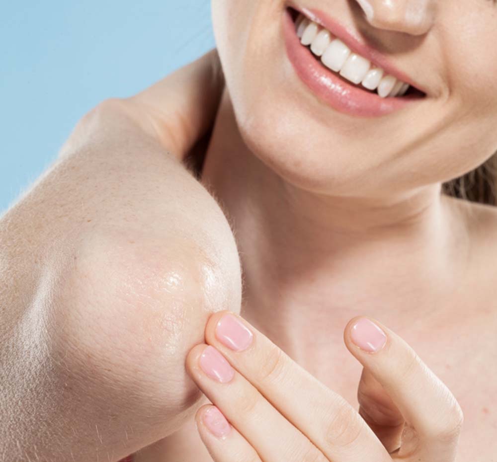 A woman is applying Marshmallow Melt All-Purpose Shea Butter Balm by FarmHouse Fresh on her skin, made with a highly effective skin conditioning formula.