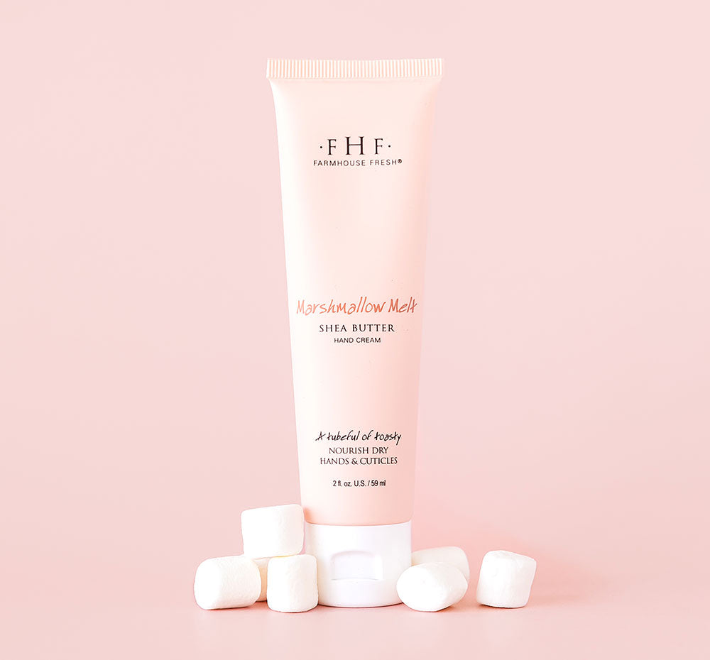 A tube of FarmHouse Fresh’s nourishing Marshmallow Melt Shea Butter for hands for dry skin with marshmallows next to it.