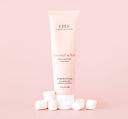 A tube of FarmHouse Fresh’s nourishing Marshmallow Melt Shea Butter for hands for dry skin with marshmallows next to it.