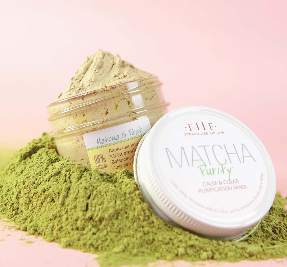 A jar of Matcha Purity Purification Face Mask by FarmHouse Fresh on top of organic matcha that represents the locally sourced ingredients that this skincare product is made with.