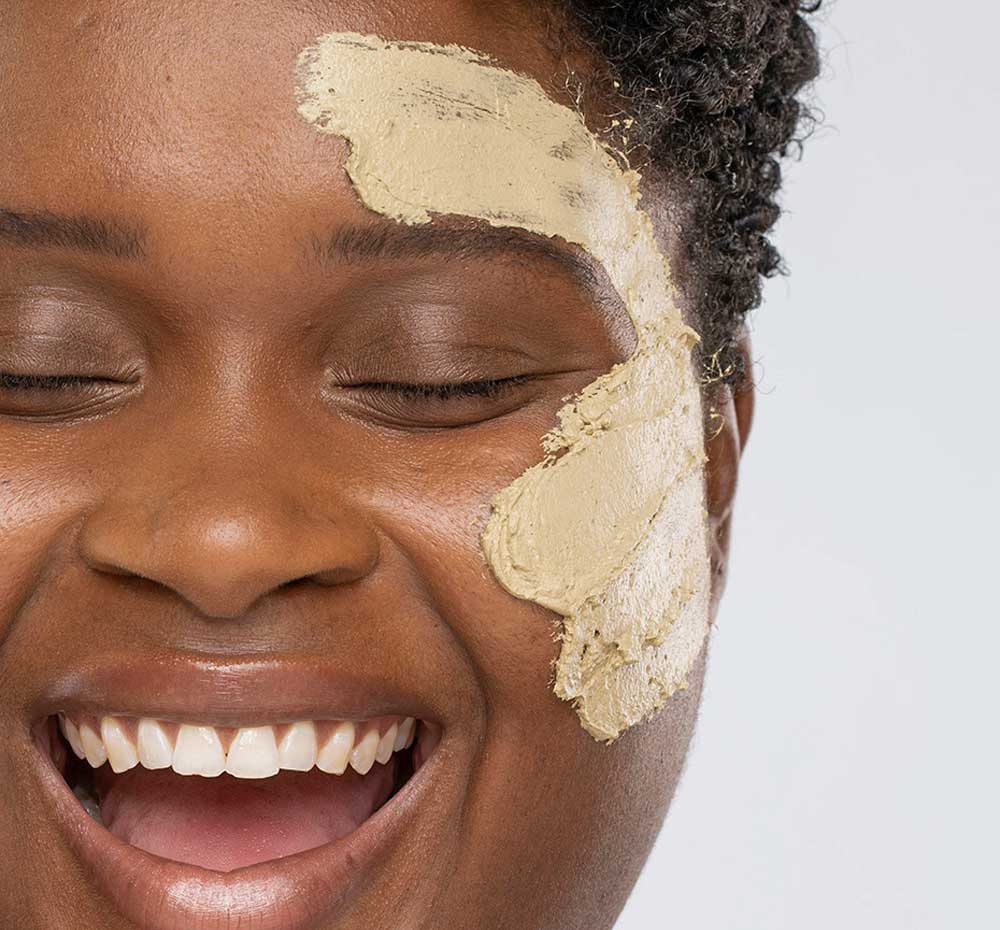 A woman with Matcha Purity Mask by FarmHouse Fresh on her face, a calming and clearing face mask made with locally sources soothing ingredients.