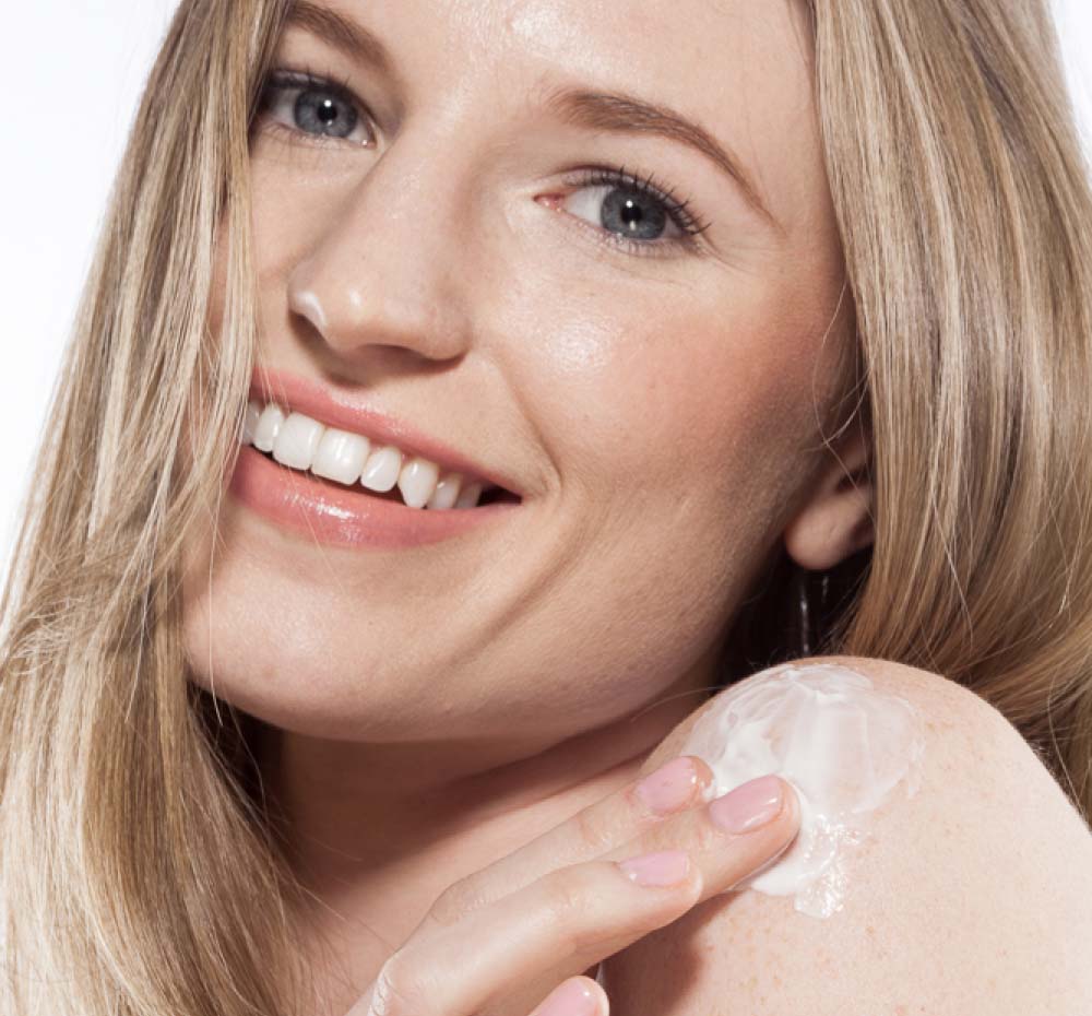 A woman is applying FarmHouse Fresh Maypop body cream on her arm to moisturize and soothe dry skin.