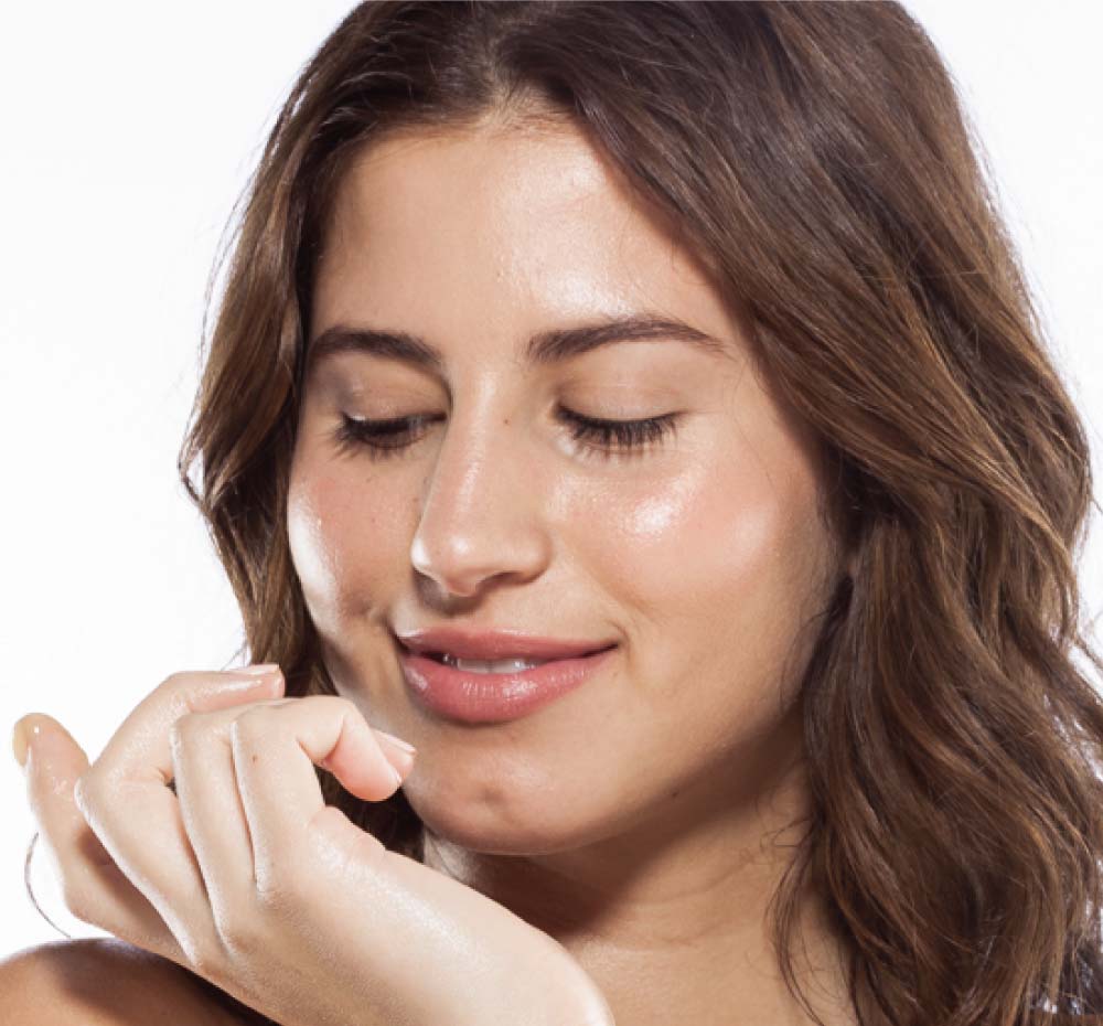 A woman is showing her glowing and plump complexion after using FarmHouse Fresh Mighty Brighty Vitamin C Brightening face moisturizer.