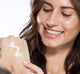 A woman is applying lightweight Sweet Cream milk lotion by FarmHouse Fresh on her hand to hydrate skin.