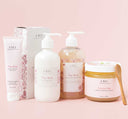 A set of Pink Bubbletini body care products by Farmhouse Fresh, including body polish, body wash, shea butter body lotion and a hand cream, displayed on a pink background.