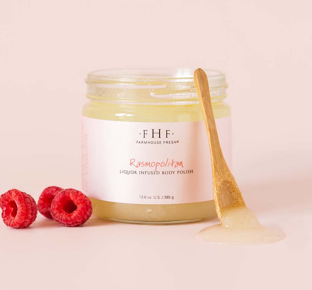 A jar filled with nourishing Rasmopolitan Liquor Infused Body Polish and a wooden spoon from Farmhouse Fresh.