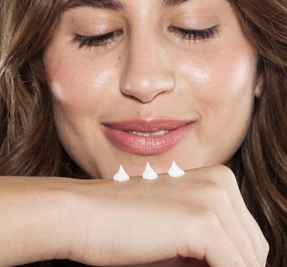 A woman is applying on her hand rich moisturizing Pink Moon shea butter hand cream by FarmHouse Fresh to calm her dry skin.