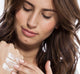 A woman is applying on her hand rich moisturizing Pink Moon shea butter by FarmHouse Fresh to calm her dry skin.