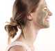 A woman with Guac Star Avocado Mask on her face, smiling, showing the cooling and hydrating effect of the mask.