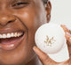 A smiling woman is holding a refreshing, all natural FarmHouse Fresh Rosemary-Mint Bath bomb with CBD.