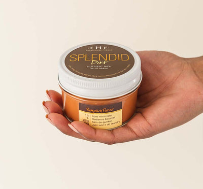 A hand holding a jar of Splendid Dirt Nutrient Mud Mask with Organic Pumpkin Puree from FarmHouse Fresh made for red, blotchy, and oily skin.