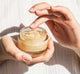 Woman’s hands holding a jar of FarmHouse Fresh Sunflower Superbalm Firming Peptide Boost face balm made with nourishing golden organic sunflower seed oil.