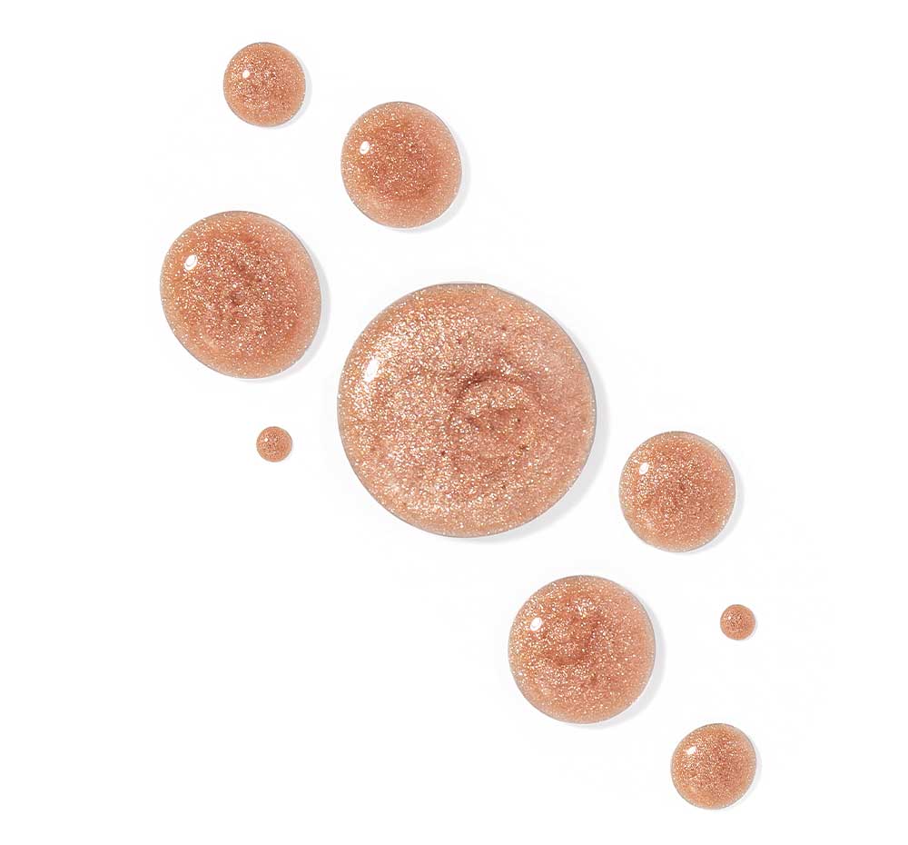 Drops of FarmHouse Fresh Sunshine Silk Shimmer Air Oil on white background, demonstrating the natural mica minerals that give skin a beautiful glow.