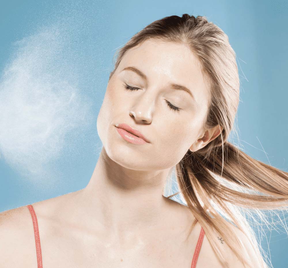 A woman is misting her face with Super Lettuce Facial Tonic by Farmhouse Fresh to hydrate and refresh her skin.