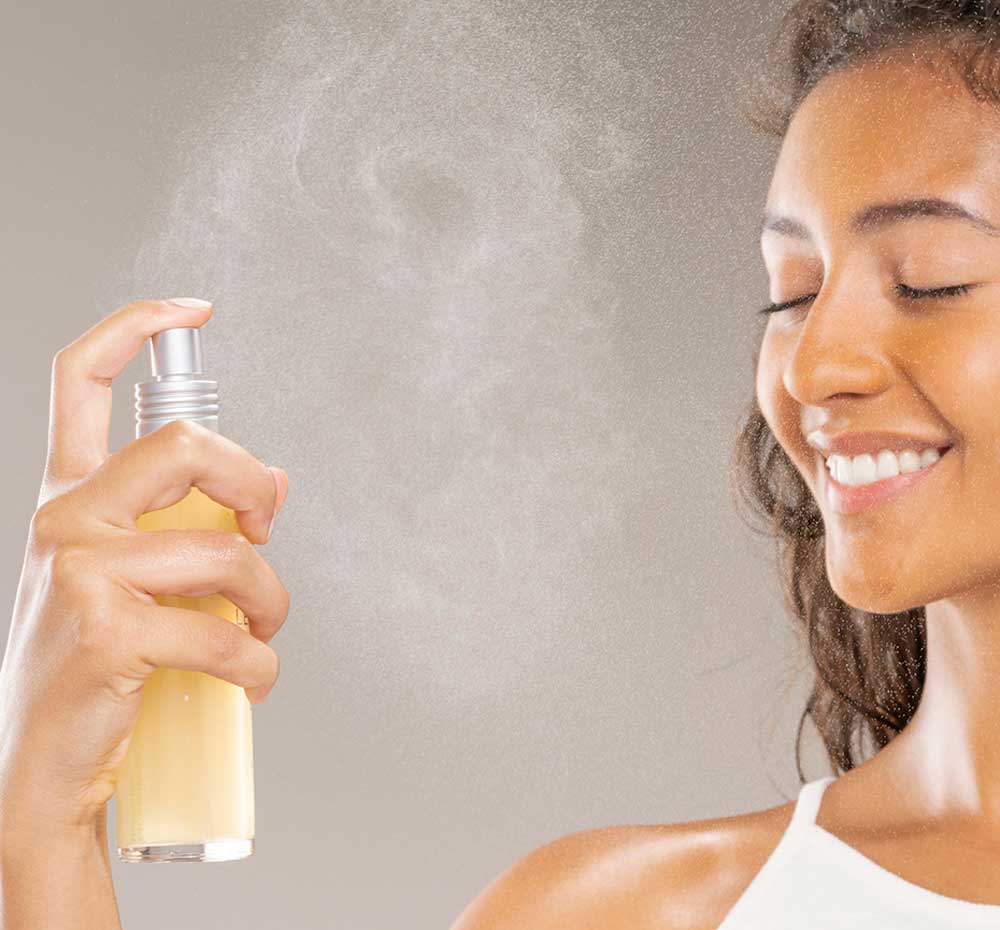 A woman is spraying her face with Super Lettuce Facial Tonic by Farmhouse Fresh to clarify and refresh her complexion.