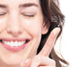 A smiling woman is holding a pea-size amount of FarmHouse Fresh Sunflower Superbalm Firming Peptide Boost face balm on her finger.