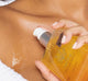 A woman is applying FarmHouse Fresh Swell Being Hemp Relaxation Body Oil with CBD on her body to nourish and soften her dry skin.