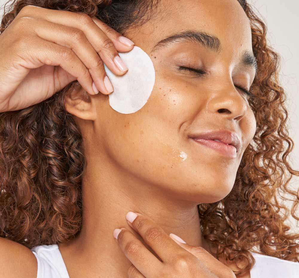 A woman is swiping her face with FarmHouse Fresh Thyme Swipe Balancing Peel Pad to soften, smooth and refresh her complexion.