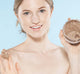A woman holding a jar of Triple Shot Caramel Coffee body scrub by FarmHouse Fresh, showing its whipped, creamy texture that is perfect for gently polishing dry, dull skin.
