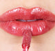 A woman is applying FarmHouse Fresh Vitamin Glaze Lip Gloss in Berry color that brings color and hydrates lips.