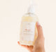 A hand holding a bottle of FarmHouse Fresh Whoopie body wash that soothes skin irritations.