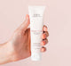 A hand holding a tube of thick and moisturizing Whoopie hand cream by Farmhouse Fresh.