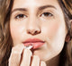 A woman is applying Whoopie Hydrating Lip Balm by Farmhouse Fresh to nourish and moisturize her dry lips.