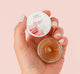 A hand holding natural and gentle Whoopie Lip Polish by Farmhouse Fresh.