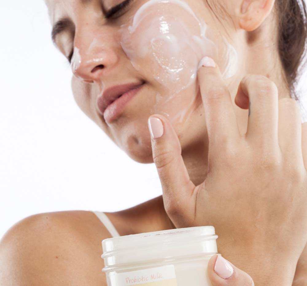 A woman is applying Will Dew Organic Probiotic Milk Balancing Mask by FarmHouse Fresh on her face to reduce dryness, redness and the look of wrinkles.